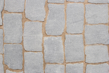 Texture of fragment of gray path made of masonry with sand in seams between paving stones. Top view