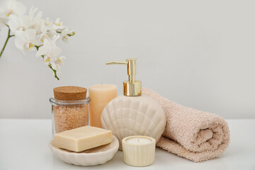 Set of bath supplies with candle on light background