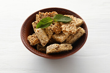 Bowl of tasty sesame kozinaki on light wooden background
