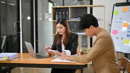 Professional Asian businesswoman focused on her tasks, working with her male colleague