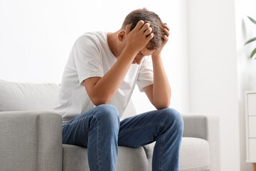 Stressed young man sitting on sofa at home