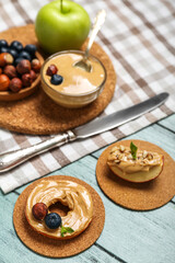 Tasty apple round and wedge with nut butter on color wooden table