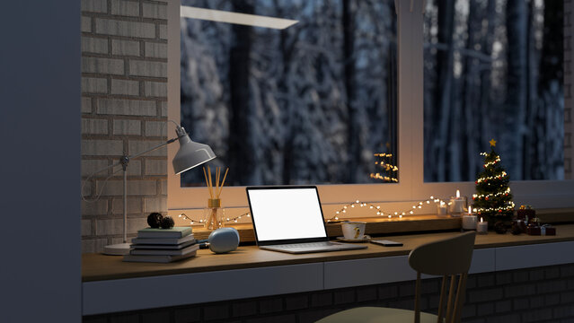Working space with laptop mockup, Christmas tree, Christmas lights on table against the window