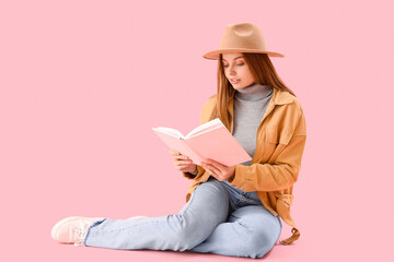 Young woman reading book on pink background