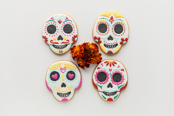 Skull shaped cookies with marigold flowers on white background. El Dia de Muertos