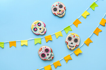 Skull shaped cookies and flags on blue background. El Dia de Muertos