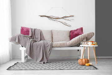 Table with calendar, Halloween pumpkins and couch in modern living room