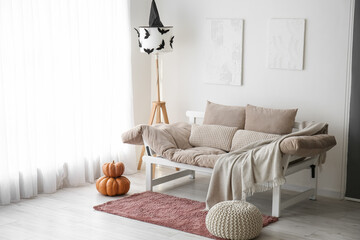 Interior of light living room with couch, Halloween pumpkins and lamp