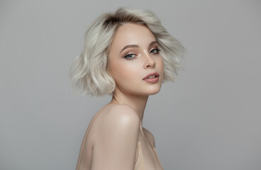 Portrait of a beautiful blonde girl with a short haircut. Gray background. - 539079461