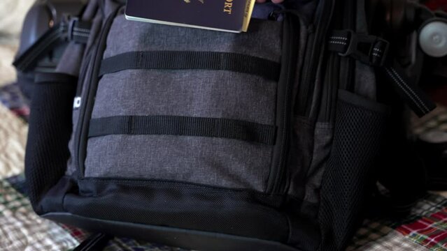 Man's hand seen putting his passport and travel documents in his carry on luggage - isolated close up