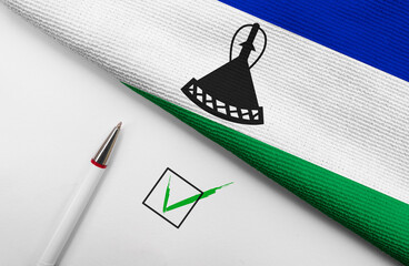 Pencil, Flag of Lesotho and check mark on paper sheet
