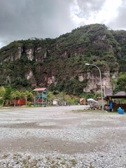 An entrance gate of the tourist attraction, a hill with a background foggy sky.