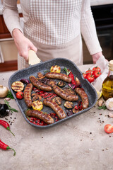 Grilled sausages and vegetables on a grill frying pan on a domestic kitchen