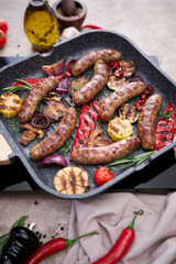 Grilled sausages and vegetables on a grill frying pan on a domestic kitchen