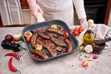 Grilled sausages and vegetables on a grill frying pan on a domestic kitchen