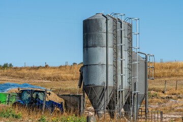 Aerial view of industrial metal silos for product storage and an agricultural tractor © João Macedo/Wirestock Creators