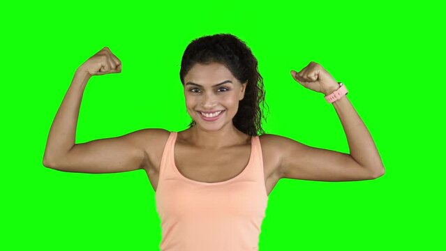 Young woman showing her strong biceps on studio