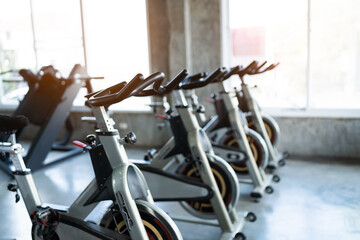 Fitness center club with training exercise bikes. Modern gym interior with equipment. Workout with...