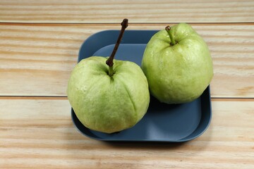Pile of fresh and organic guava serving on the plate. Mock up of traditional tropical fruit product in Asia market.