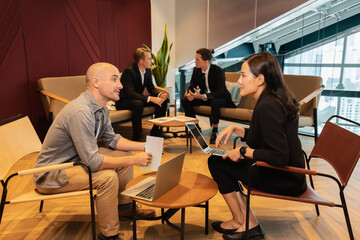 man and woman working together with two businessman discussing at background. businesswoman using laptop in workplace. colleague man and woman working in modern office