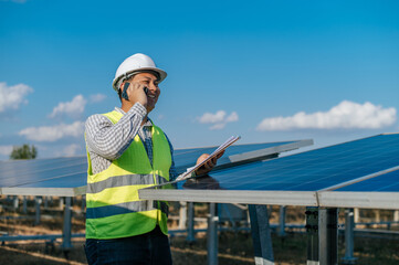 Young engineer talking on smartphone while working at solar farm