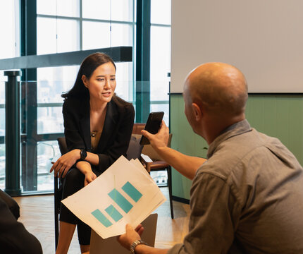 young businesswoman meeting online via mobile phone of businessman about financial graph in workplace with window background. colleague man and woman working in modern office