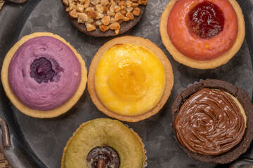 Egg Tart or Baked Cheese Tart in various flavors, purple potato, chocolate, vanilla cream, lemon, green tea and almond cream.