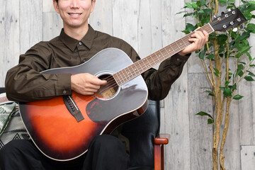 屋内でギターを弾く男性