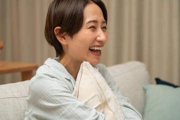 ソファで笑顔のパジャマ姿の日本人女性
