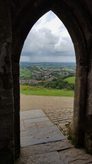 A view from inside iconic St Michael's Tower, the Tor, through arch doorway with rural farming countryside landscape of Glastonbury, Somerset in England UK