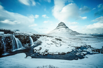 Winter landscape with rising sun on Kirkjufellsfoss waterfall and Kirkjufell mountain, Iceland,...