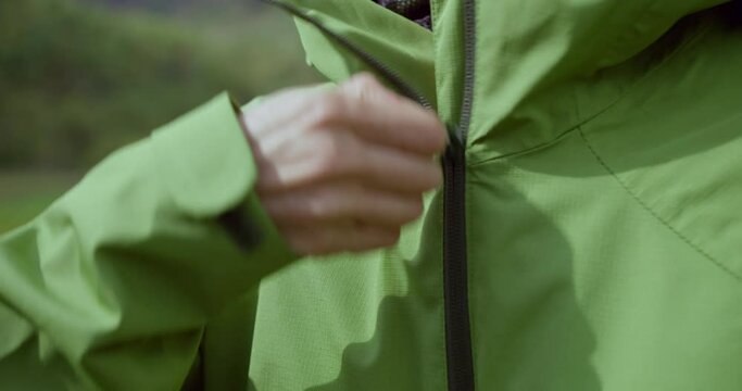 Female hiker pulling zip on sport jacket in autumn valley in mountain. Close-up view