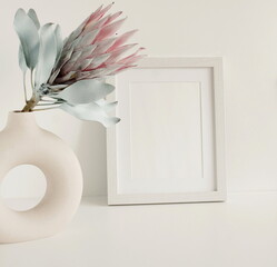 White frame mockup, protea flower in a vase  composition on white background.Copy space.