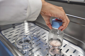 Hand of researcher with nitrile grove, The researcher warm the cell culture media in the water bath...