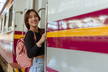 woman wearing black long sleeve t-shirt carrying backpack on shouder holding digial camera in hands standing on stair of train at railway station,travel concept,social network technology concept