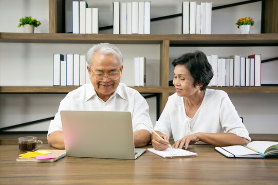 Senior Adult Reading Newspaper Online on laptop in livingroom.