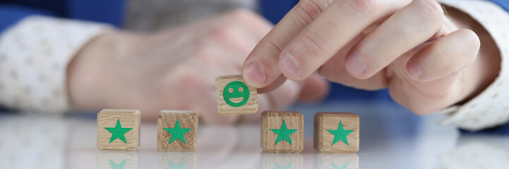 Client is holding smiling smiley face on wooden cube