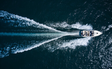Big boat in motion on the water top view. Luxury yacht with people moving fast on dark blue water...