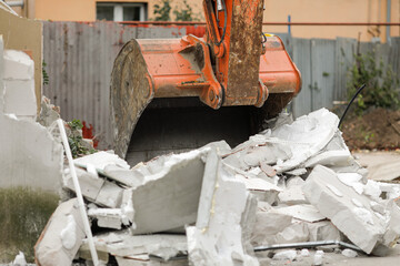 Details with an excavator bucket (scoop) used to demolish an AAC small building.