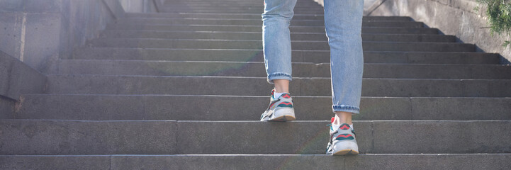 Athletic woman climbs stairs in sneakers with glare or sunspot