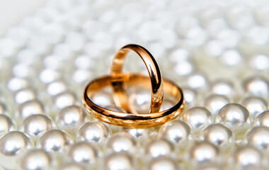 Gold wedding rings lie on a pearl necklace
