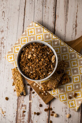 Energy breakfast. Chocolate granola with dried fruits in a bowl, various granola bars on a light wooden background.
