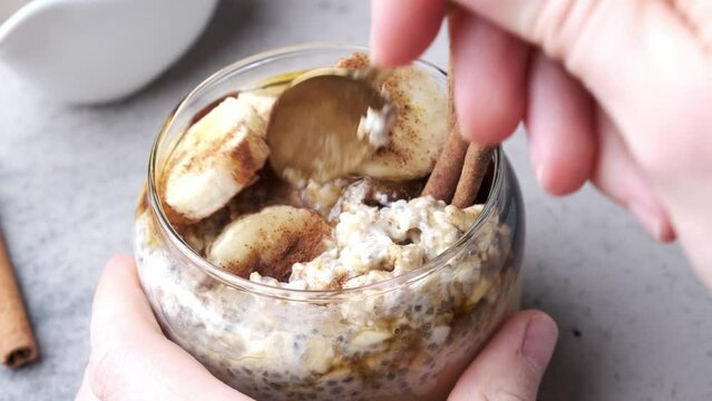 Chia pudding jar with banana, peanut butter, cinnamon and maple syrup, dark background. Winter breakfast concept.