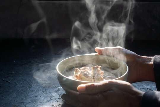 Bowl of pork bone soup. steam of hot soup with smoke wood bowl on dark background.selective focus,hot food concept