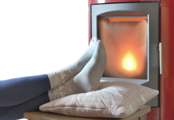 woman foot in socks in front  of a fire i n a stove 