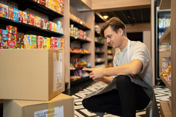 Portrait of a caucasian man working in a supermarket or retail shop and food on grocery products....