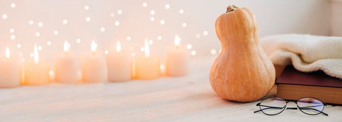 Cozy fall composition banner with pumpkin and candles book, plead and reading glasses with copy space for text