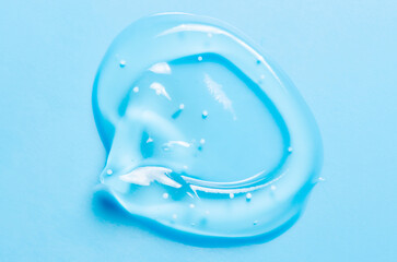 A drop of liquid gel or cosmetic serum or cleansing lotion against acne. Blue background.