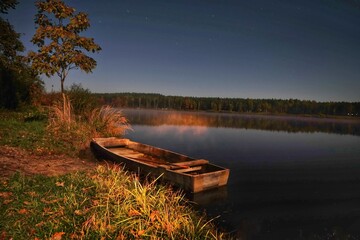 Łódka nad jeziorem w nocy. - obrazy, fototapety, plakaty