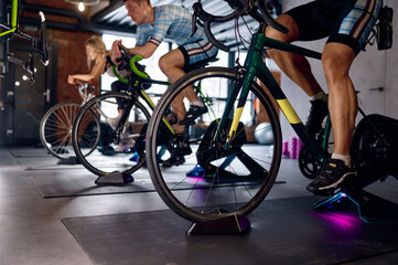 Group of sports people riding stationary bike at gym